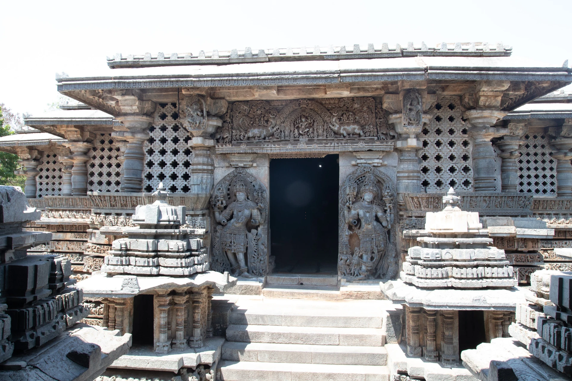 Sculptural figures in the upper panel register on the outer wall of Hoysaleswara Temple