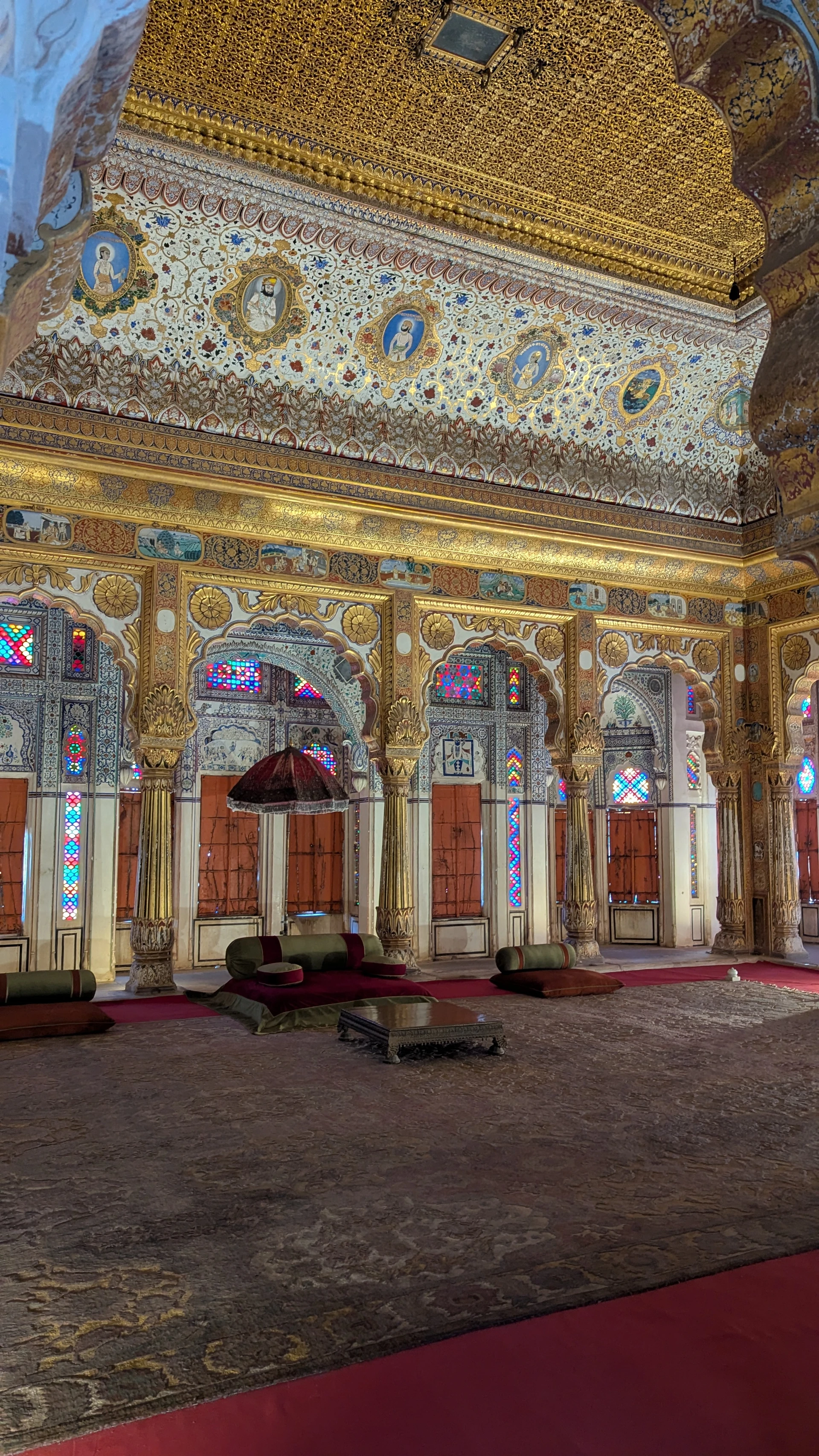Ornate interior of the Phool Mahal at Mehrangarh Fort with stained glass and gold filigree